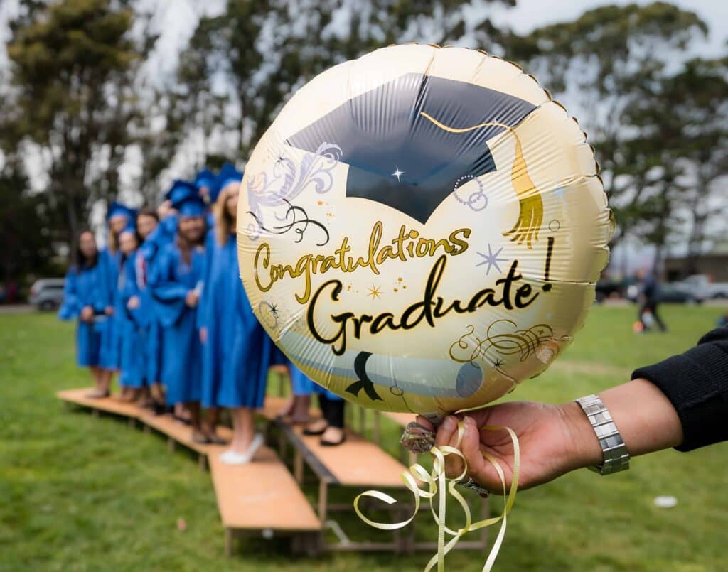 A Colourful balloon with the words " Congratulations Graduate" written on it. The Medical school graduates can be seen in the background.