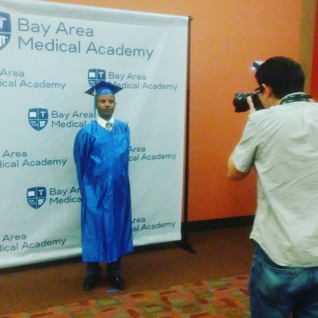 A Bay Area Medical Academy Graduate having his picture taken during the Graduation ceremony.