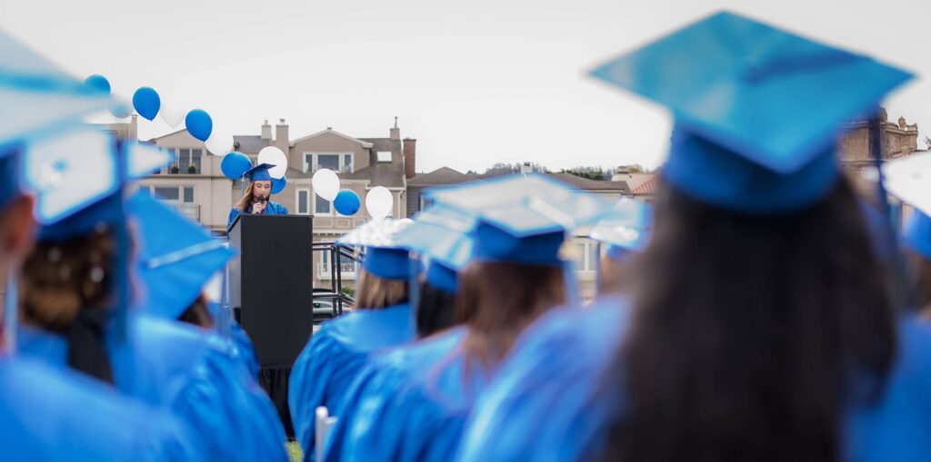 A Graduate student can be seen making a speech from the podium.