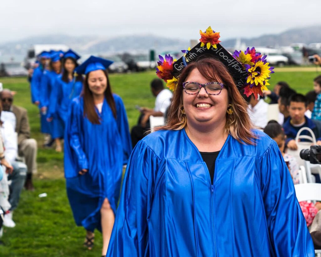 A Happy Graduate with her decorated cap smiling in front of the camera.